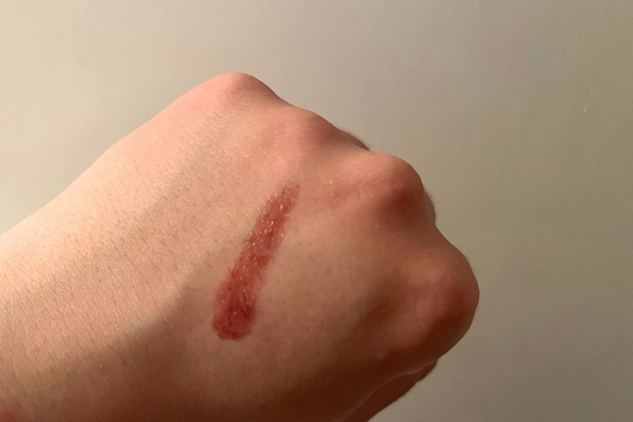 A swatch of lipstick applied on the back of a hand showcasing the texture and color