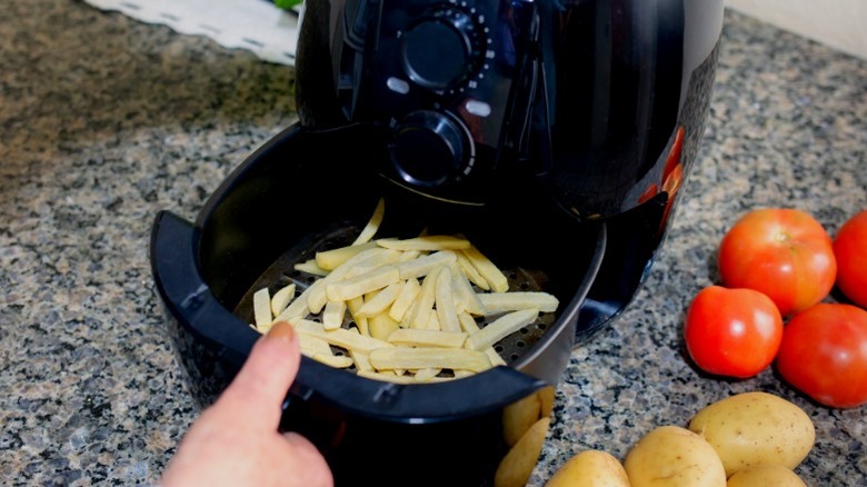 Frozen french fries in an air fryer on a granite counter