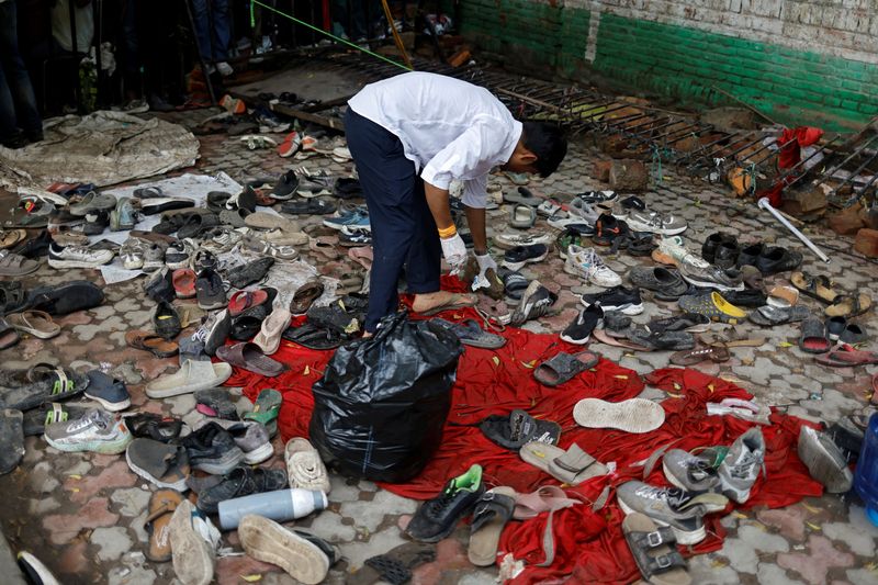 A man collects shoes left behind following a clash between police and demonstrators at a protest site on Monday, in New Delhi