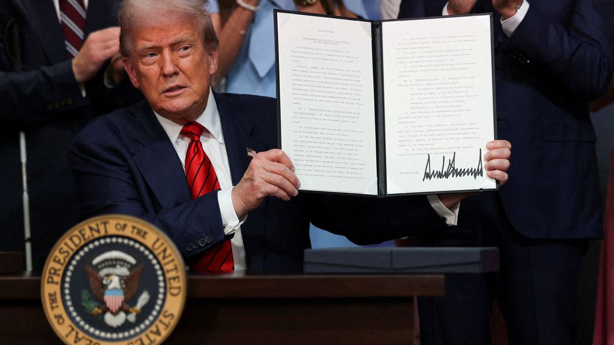 Donald Trump holds up an executive order. REUTERS/Jonathan Ernst