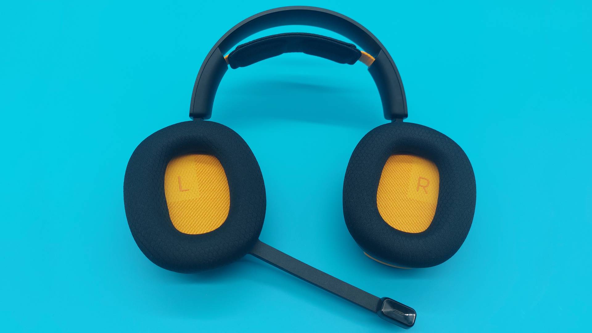 The GHS Wireless InfinitePlay seen from various angles on a blue background. This is a wireless gaming headset from Glorious. It is black all over, save for a few subtle orange accents.