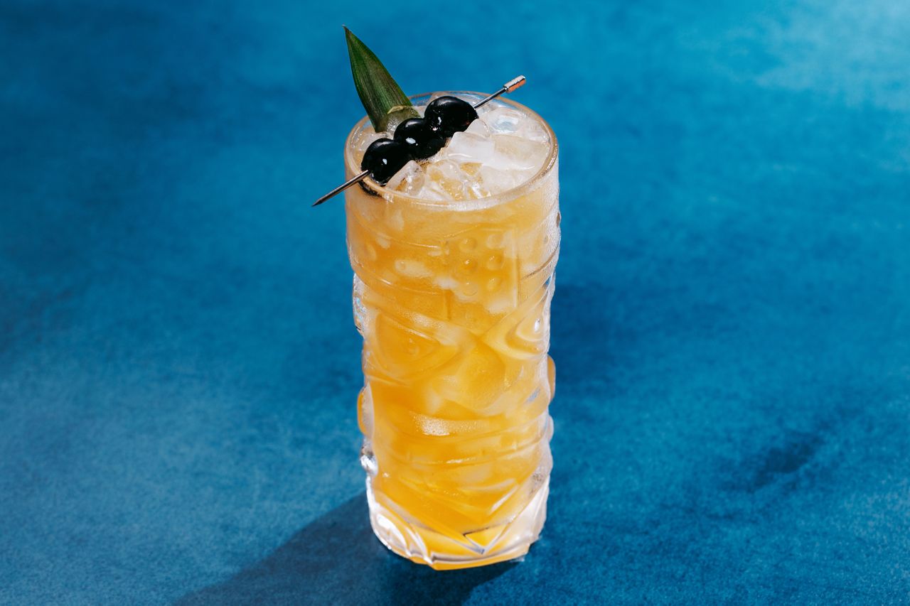 Three Dots and a Dash cocktail on a blue surface.