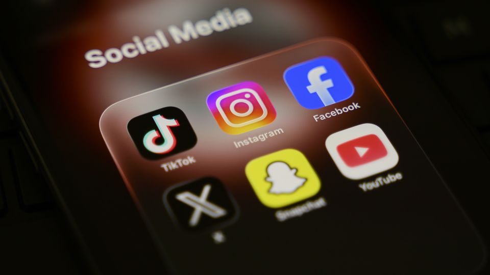 A smartphone displays a folder of social media applications, including TikTok, Instagram, Facebook, X, Snapchat, and YouTube, in Creteil, France, on March 31, 2026. - Samuel Boivin/NurPhoto/Getty Images