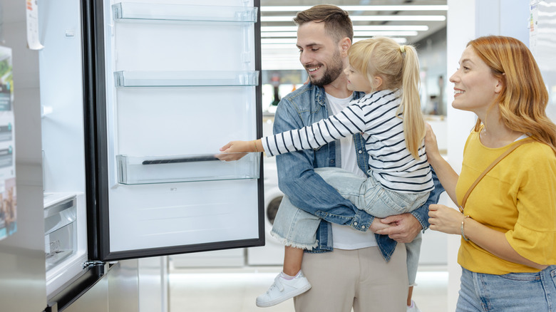 A family examines a refrigerator in a store