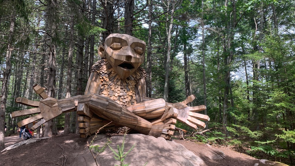 A giant troll sitting cross-legged on a rock with both hands extended and eyes closed as if meditating.