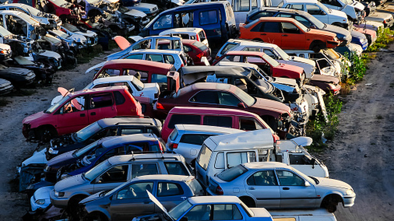 A car scrap yard in Europe, with two rows of cars facing outward from each other.