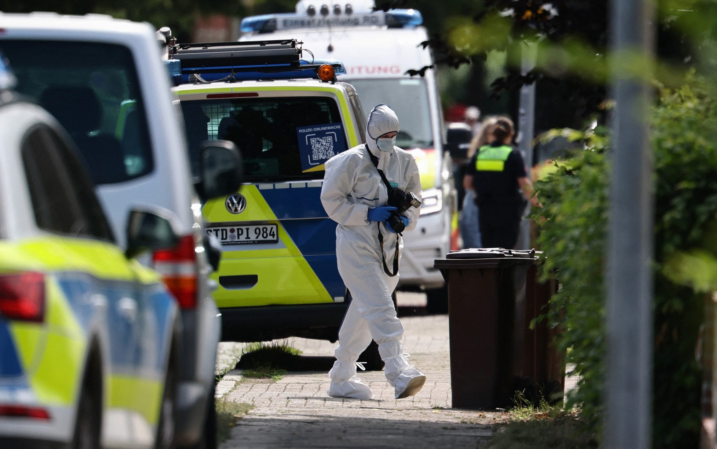 forensic Police officer with a camera works near the scene where five people were killed in a shooting in Stade