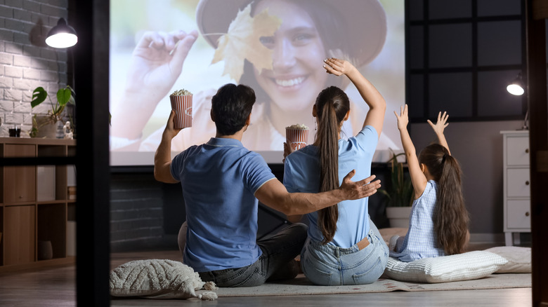 A happy family watching a movie together on a projector