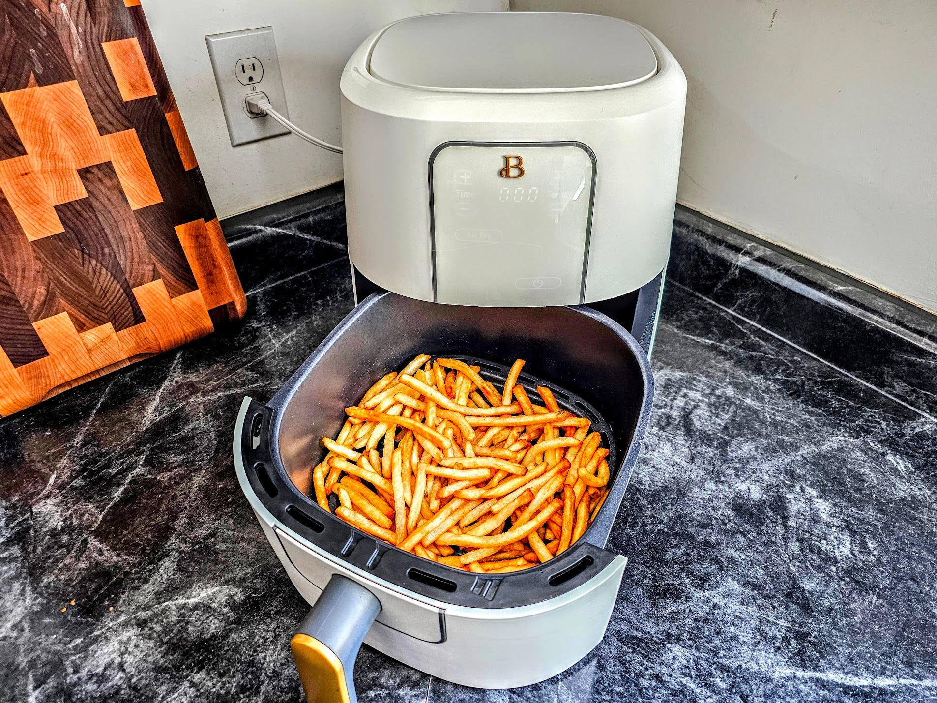The Beautiful Air Fryer is displayed with french fries in it.