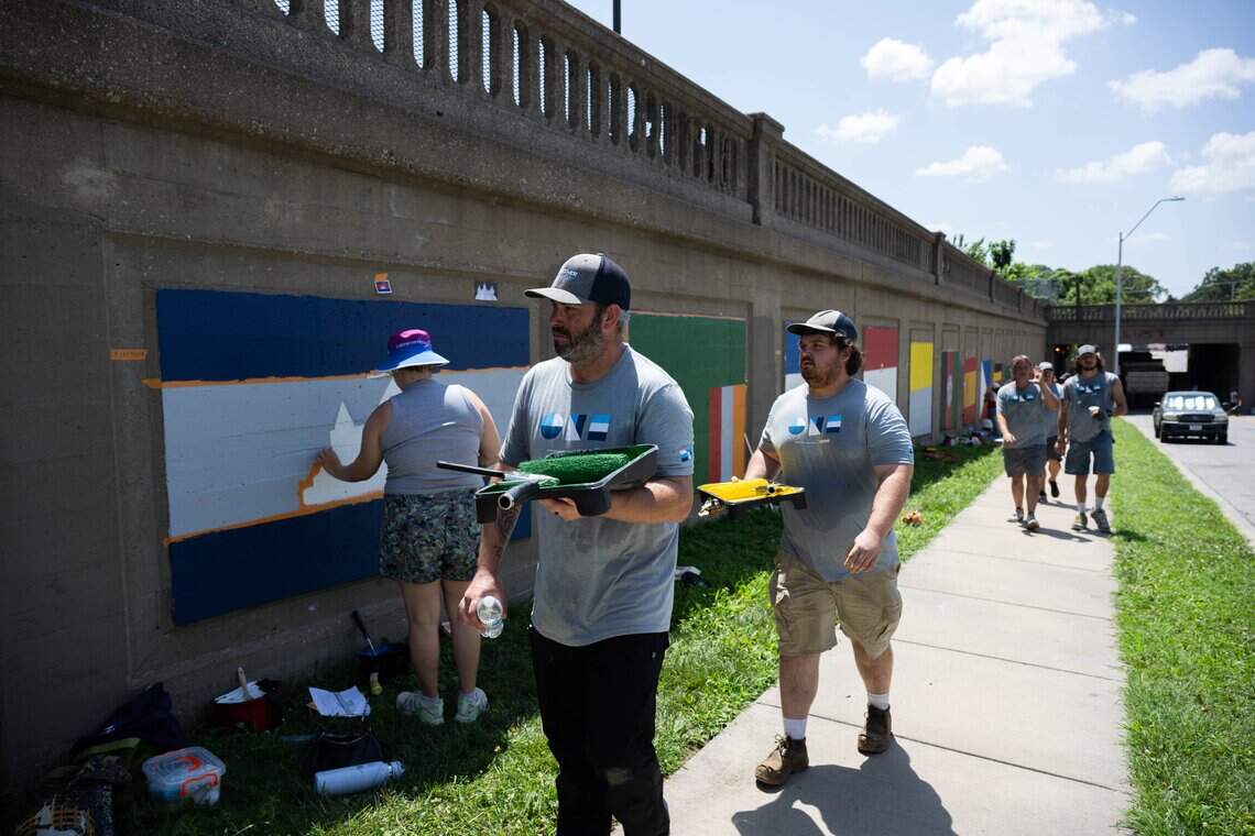 Volunteers paint a series of flag murals on Van Brunt Boulevard in Kansas City, on Monday, July 20, 2026. When complete, the mural will feature more than 100 flags representing the demographics of the neighborhood.