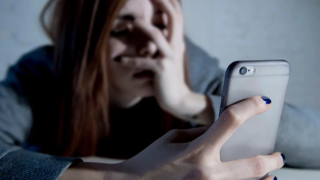 Young sad vulnerable girl using mobile phone scared and desperate.