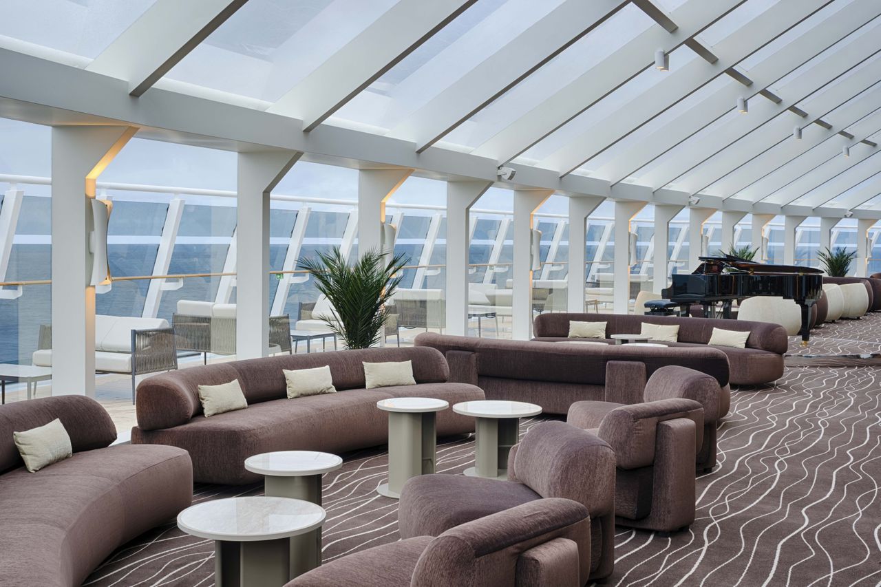 Spacious lounge area with modern curved furniture and large windows featuring a grand piano in one corner