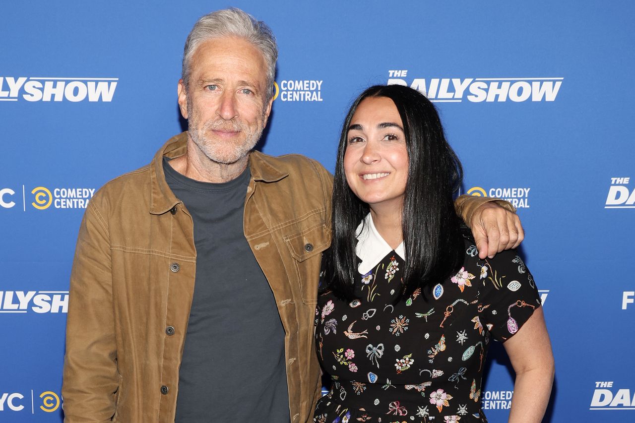 Jon Stewart posing with a person at a media event for The Daily Show