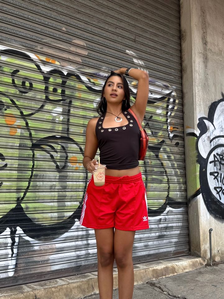 Person standing in front of a graffiticovered metal door holding a bottled drink