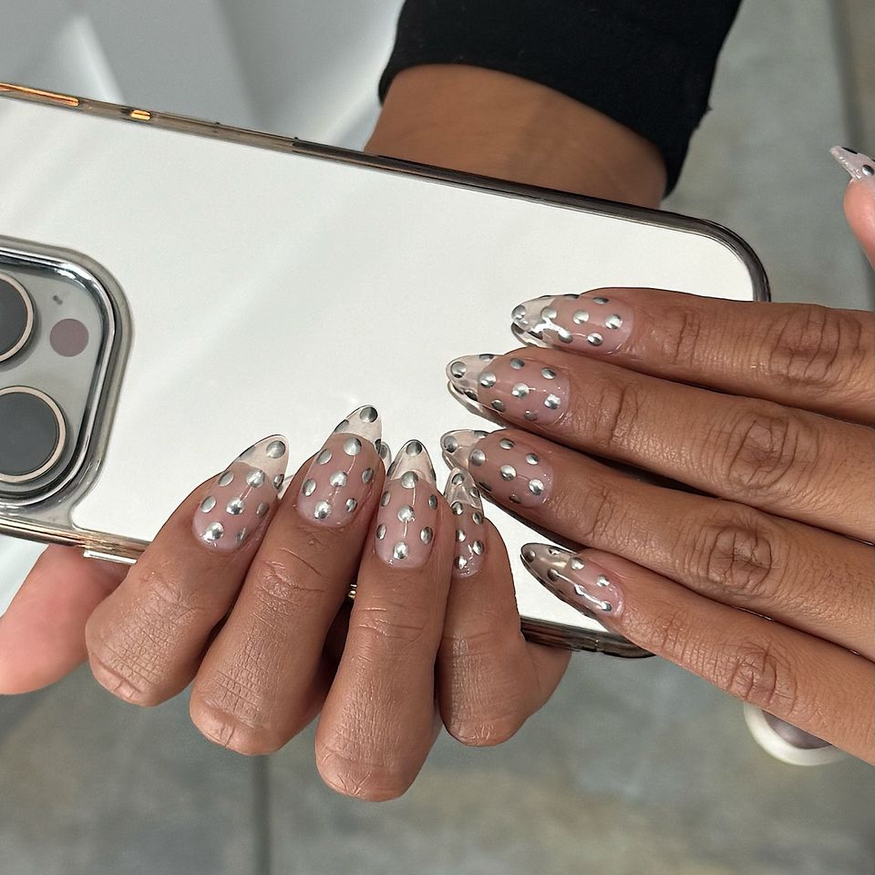 Closeup of hands holding a smartphone showing nails with decorative dot patterns