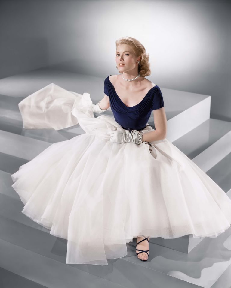 A person in an elegant dress seated on steps holding fabric