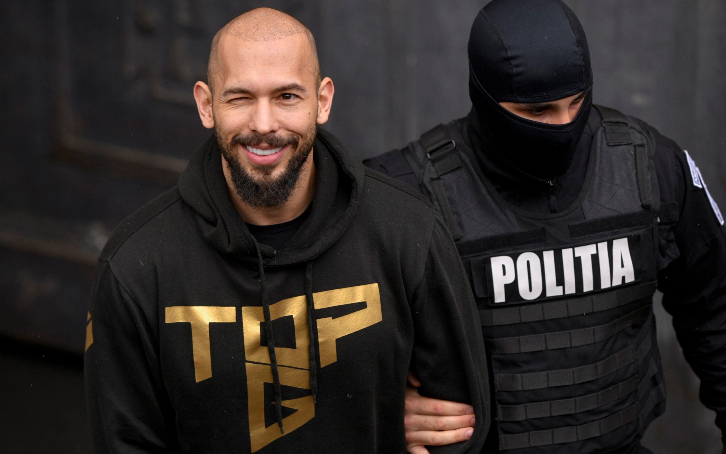 Andrew Tate is escorted in handcuffs by a Romanian police officer from the Court of Appeal in Bucharest in March 2024