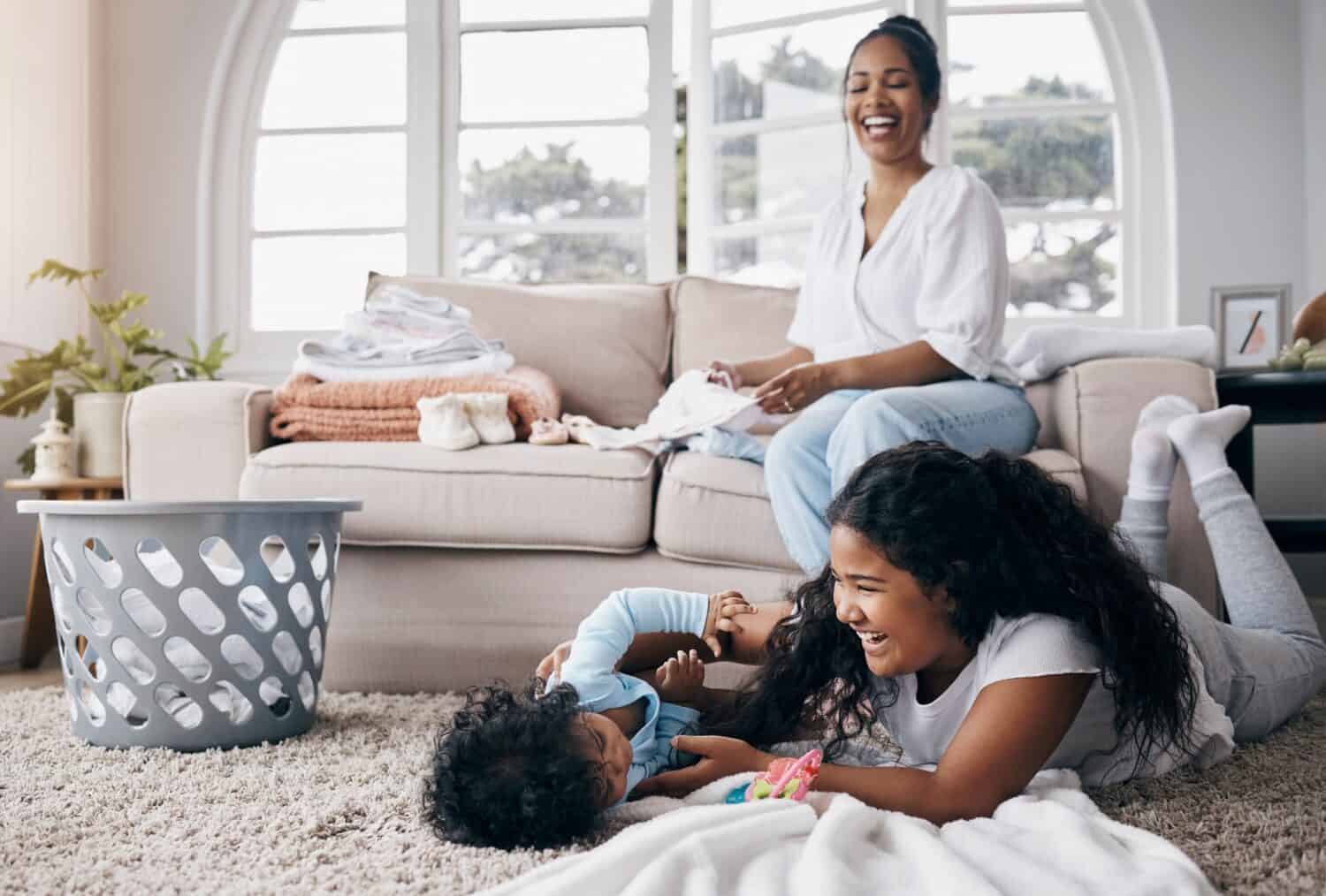 Playing, children or mother in home for laundry for organizing clothes or washing in happy family. Games, basket and mom folding fabric garment or towel for housekeeping or wellness for kids siblings