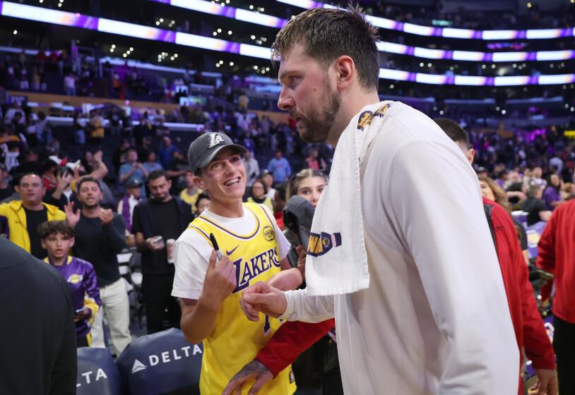 Lakers guard Luka Doncic walks off the court as a fan tries to get an autograph after a game last season.