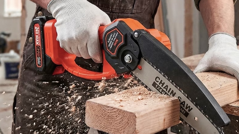 Person cutting lumber with a mini chainsaw
