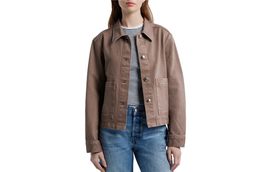 A person wearing a brown denim jacket over a striped shirt and blue jeans.