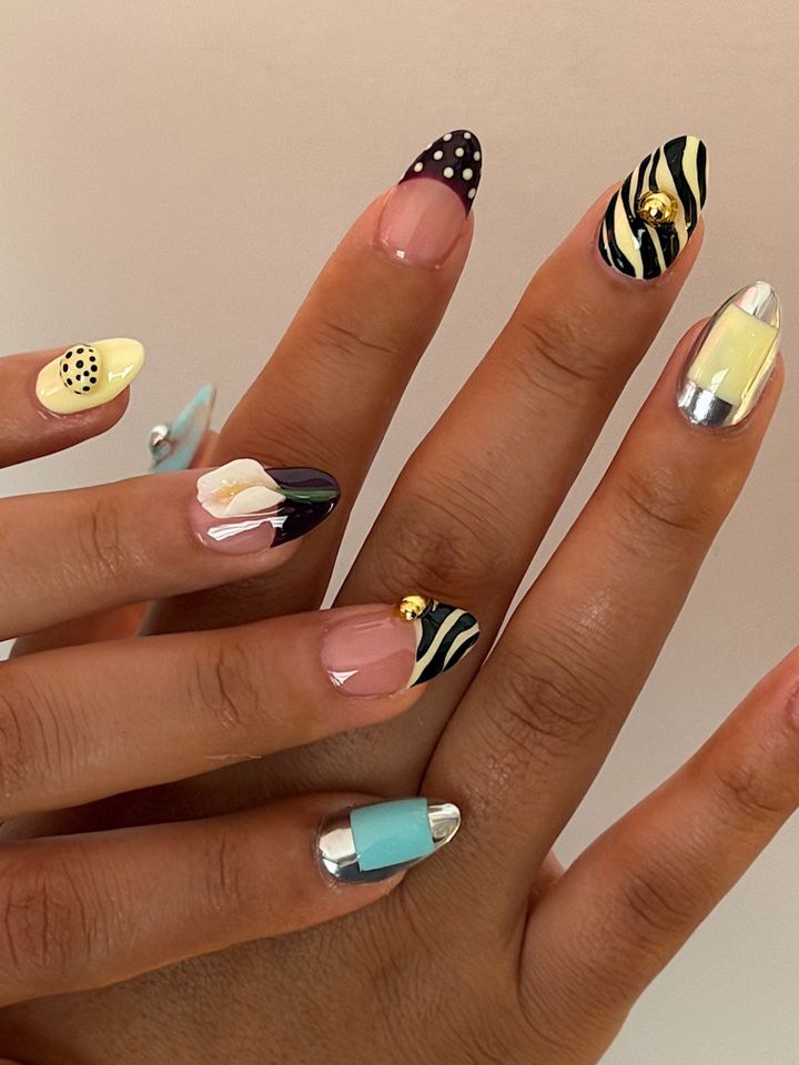 Hands displaying nails with creative and varied artistic designs including patterns and decorations