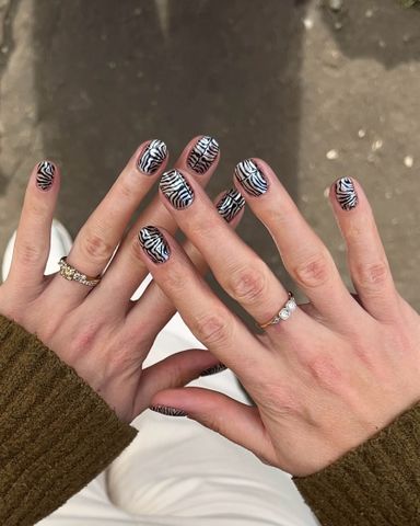 Hands with patterned nail designs and rings visible