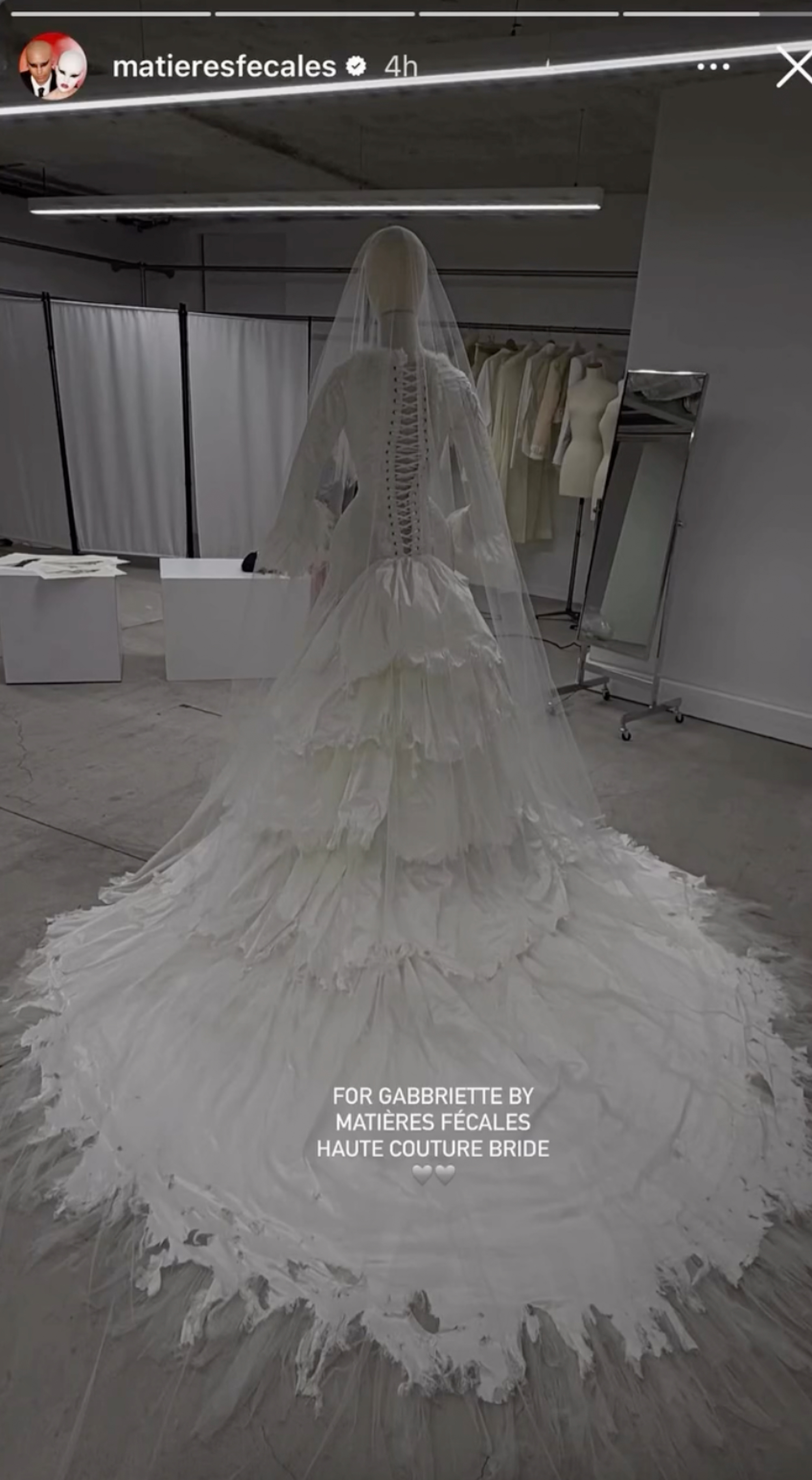 A haute couture wedding gown by Matières Fécales, featuring a corset-style back, long ruffled sleeves, and a tiered, tattered skirt with a long train.