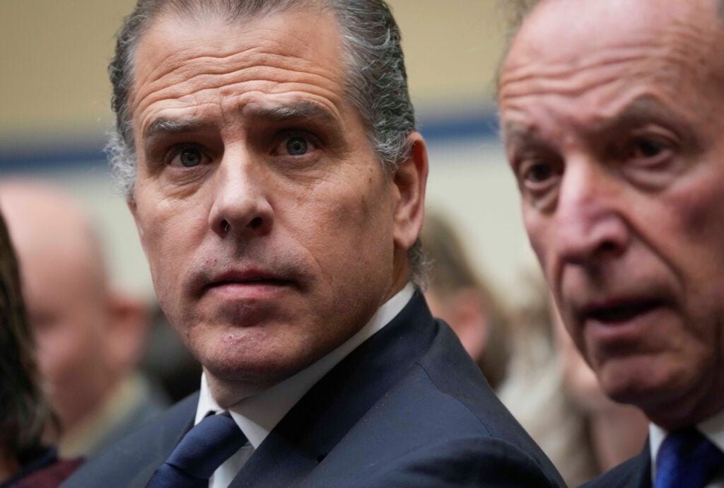 Hunter Biden, wearing a suit and tie, looks directly forward with a furrowed brow, beside Kevin Morris.