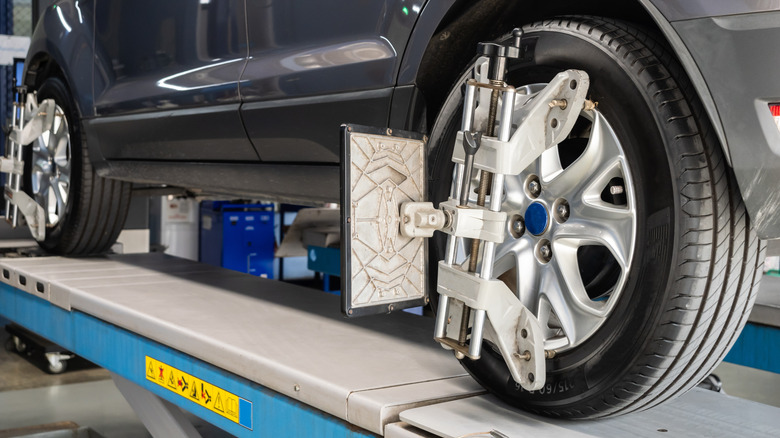 Close-up of a car on a wheel alignment rack with sensors mounted to the wheels