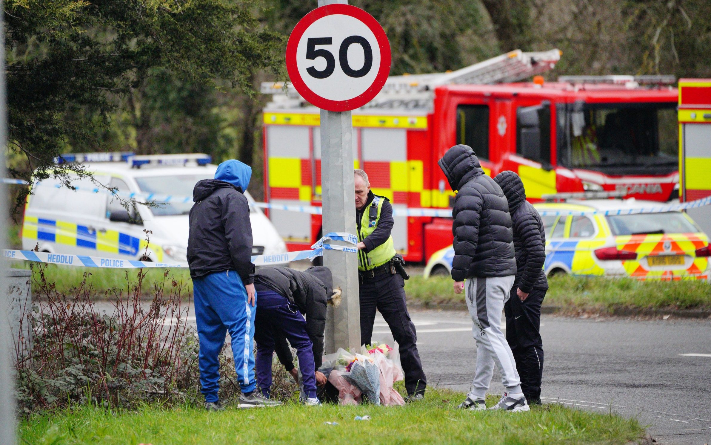 A group of people lay floral tributes near the scene in the St Mellons area of Cardiff where the car crashed