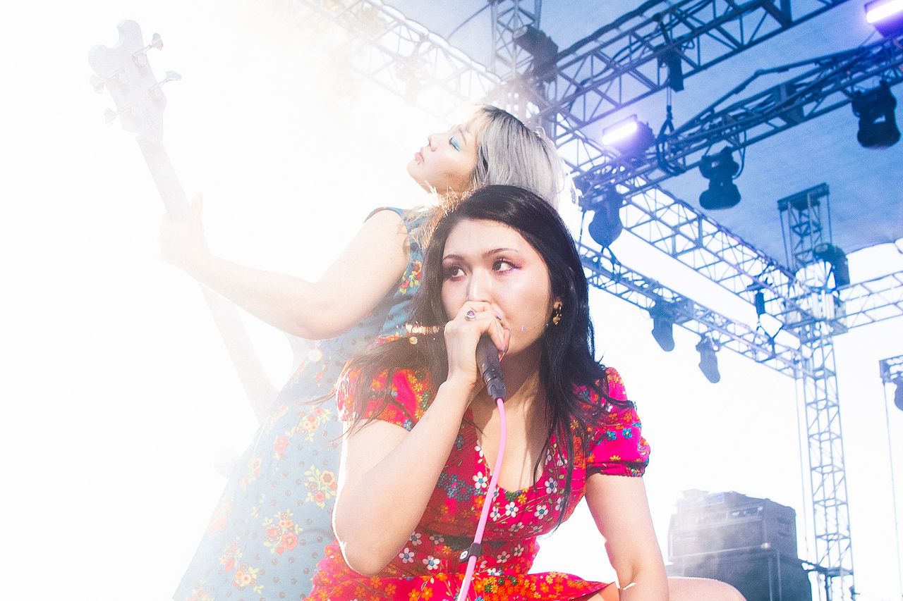 Two performers on stage one singing into a microphone and the other playing an instrument