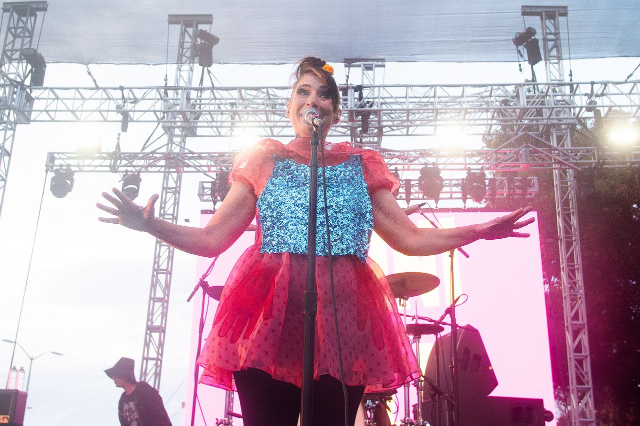 A performer on stage holding their arms out in front of stage equipment dramatic lighting enhancing the scene