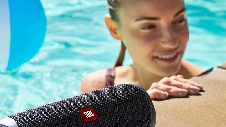 Woman using a JBL speaker at the pool