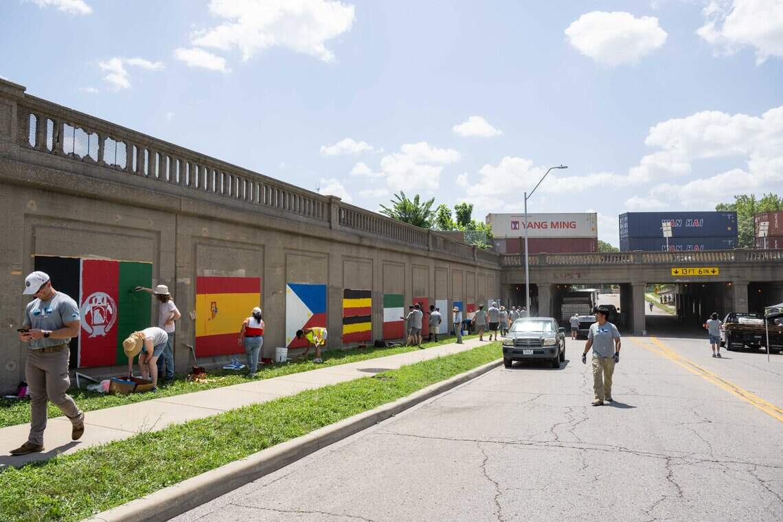 Volunteers paint a series of flag murals on Van Brunt Boulevard in Kansas City, on Monday, July 20, 2026. When complete, the mural will feature more than 100 flags representing the demographics of the neighborhood.
