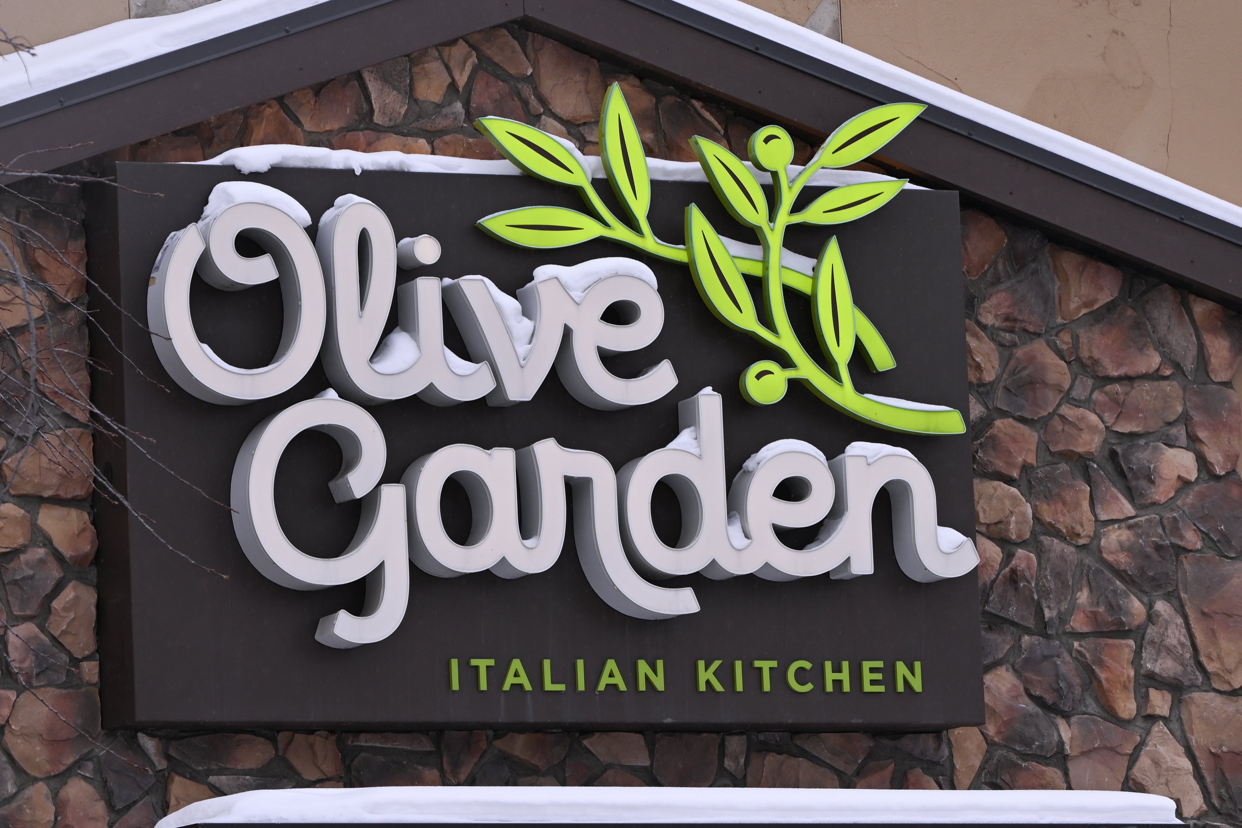 Sign for Olive Garden Italian Kitchen with stone background and snow on top