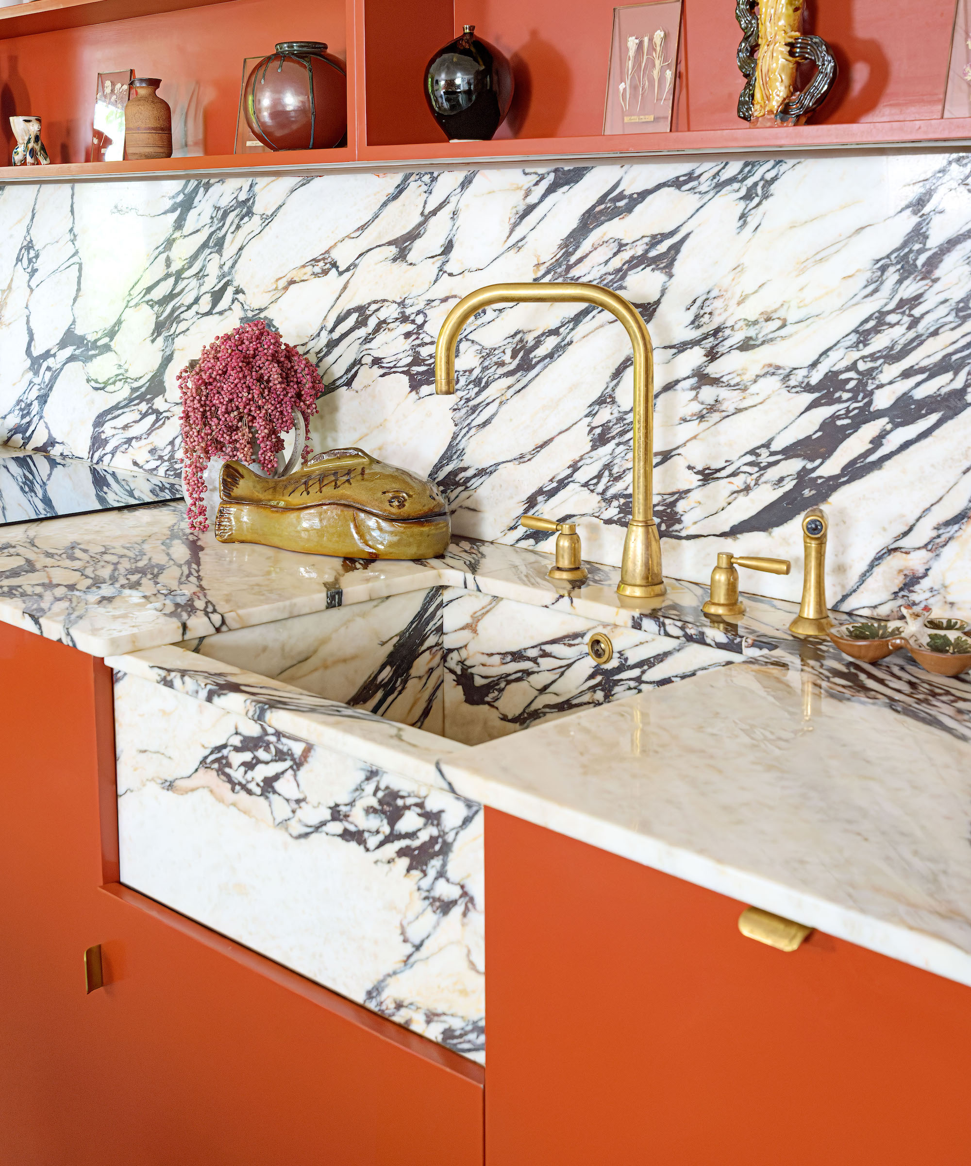 marble sink in marble worktop with orange cabinets