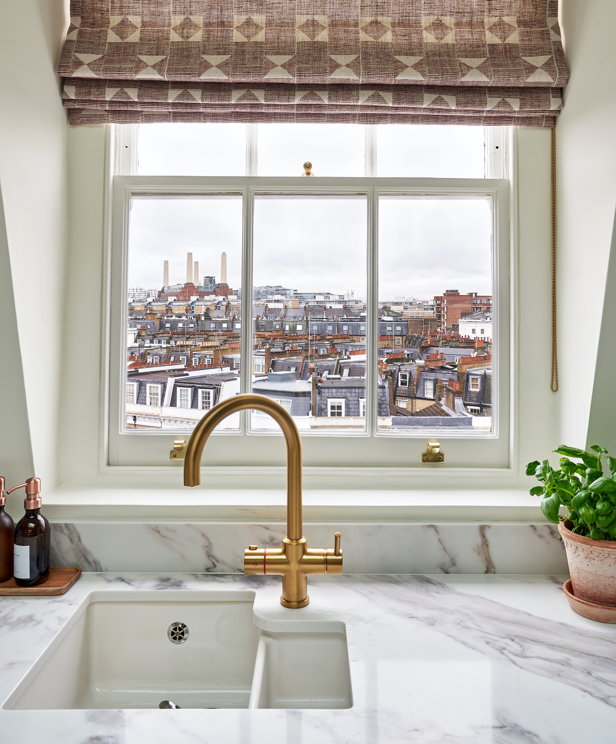 close up of kitchen sink, brass tap and marble worktops