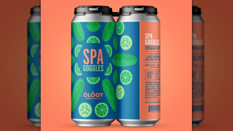 Close-up of two cans of Ology Spa Goggles Sour Gose-Style Ale on a melon-colored background
