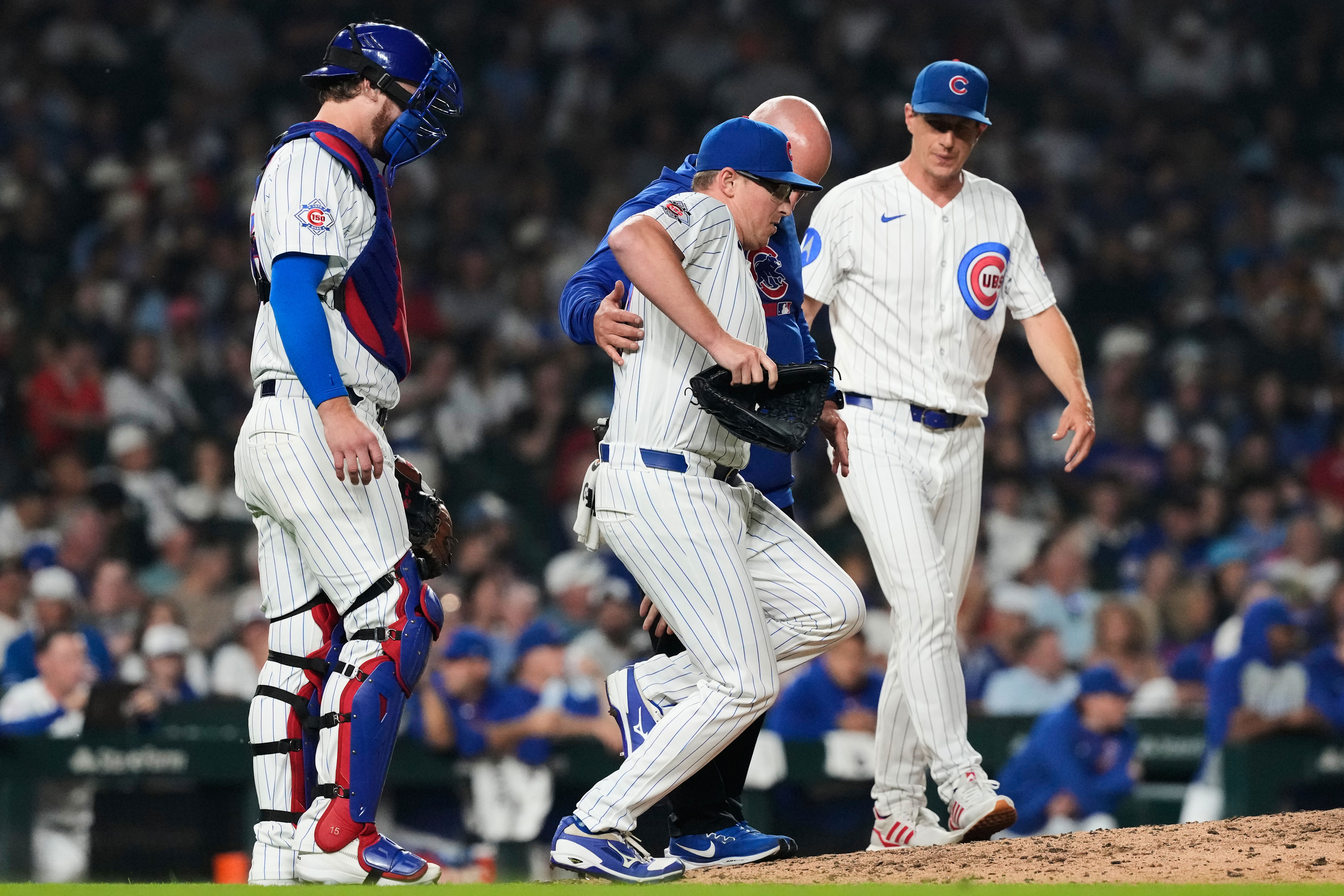 Chicago Cubs relief pitcher Trent Thornton, center, is helped by a team trainer after an injury during the 10th inning of a baseball game against the Detroit Tigers in Chicago, Monday, July 20, 2026. (AP Photo/Nam Y. Huh)