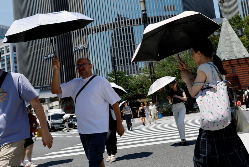 Pedestrians hold parasols to cope with the heat wave in Tokyo