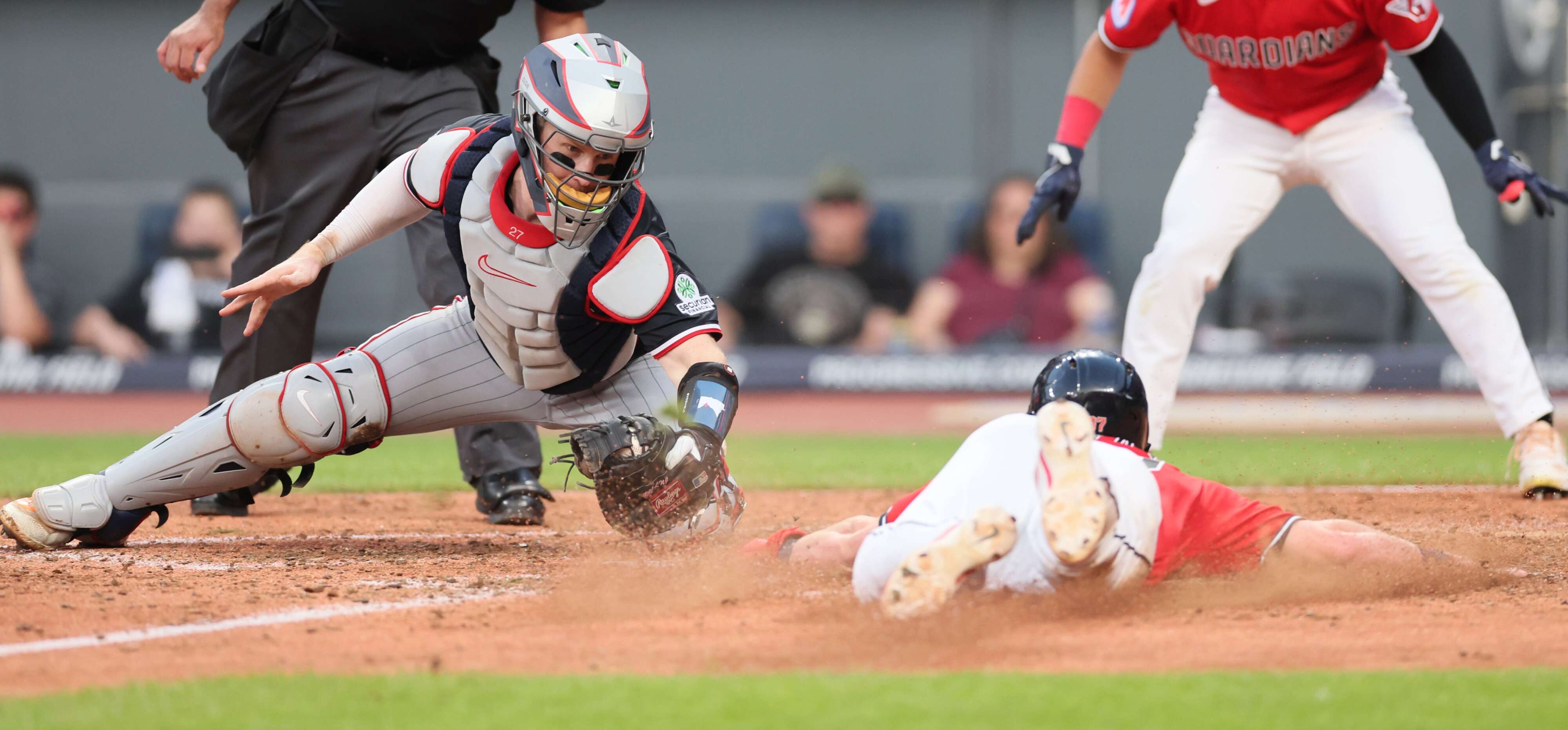 Cleveland Guardians second baseman Travis Bazzana slides to home plate as Minnesota Twins catcher Ryan Jeffers applies the tag in the sixth inning. After review, Bazzana was called safe at home.