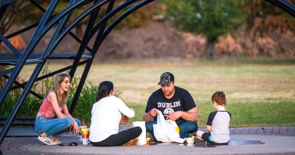 A family with a toddler and a teen, having lunch at the base of the Paris, Texas, Eiffel Tower, a roadside attraction near Dallas.