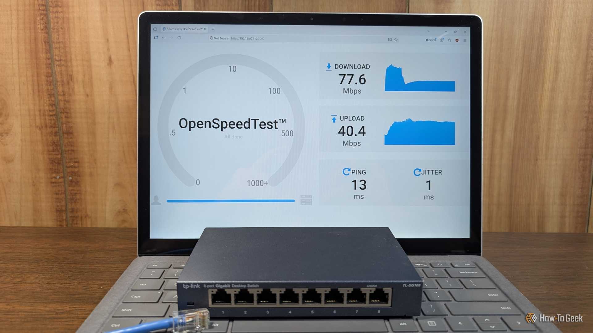 A network switch and a DIY Ethernet cable laying on a laptop showing a speed test.