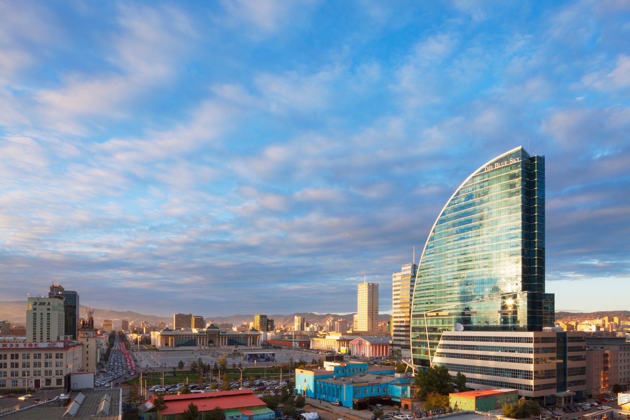 Skyline of a city with a modern curved glass building prominent