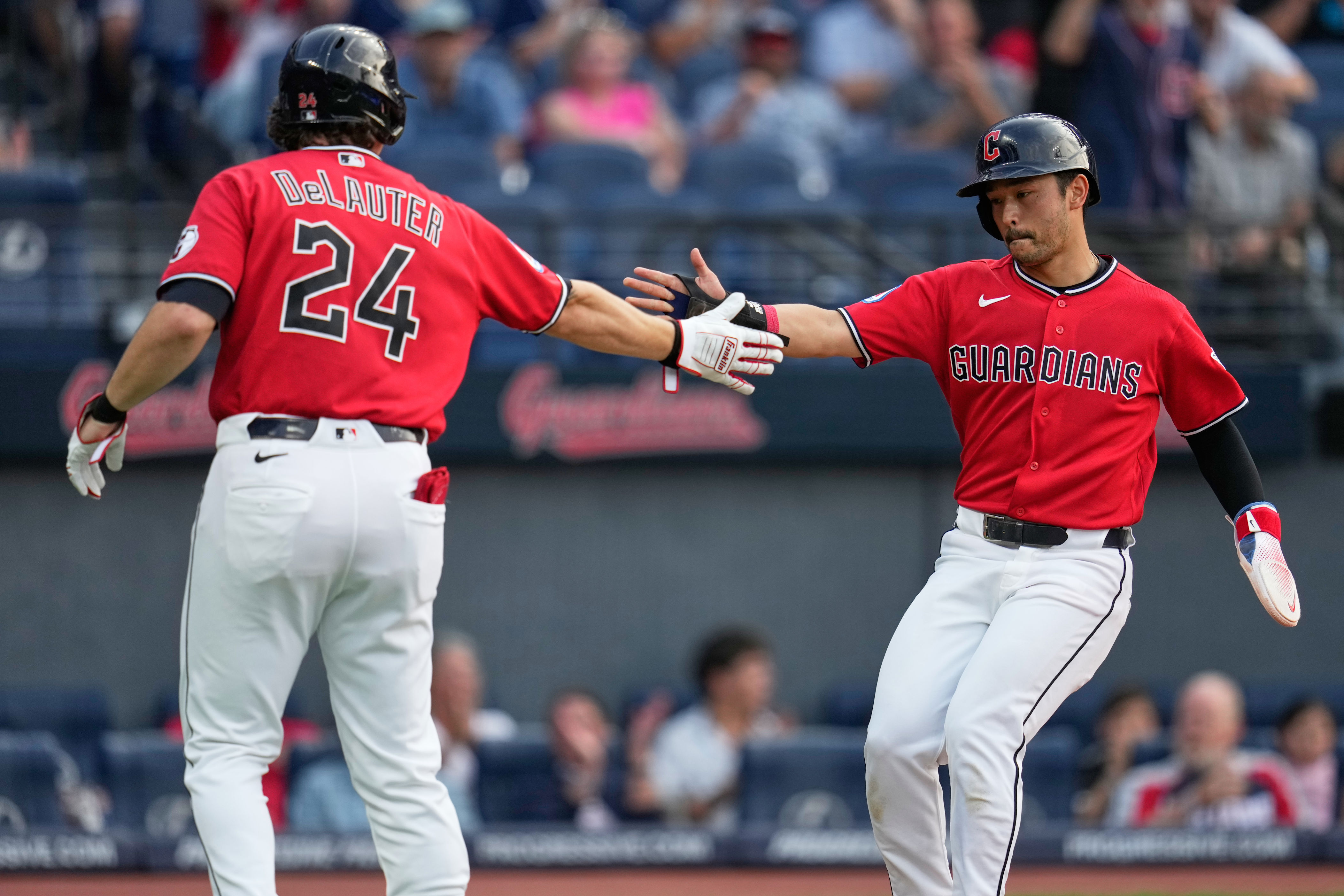 Cleveland Guardians' Steven Kwan, right, is congratulated by Chase DeLauter (24) after scoring in the third inning of a baseball game against the Minnesota Twins in Cleveland, Tuesday, July 21, 2026. (AP Photo/Sue Ogrocki)