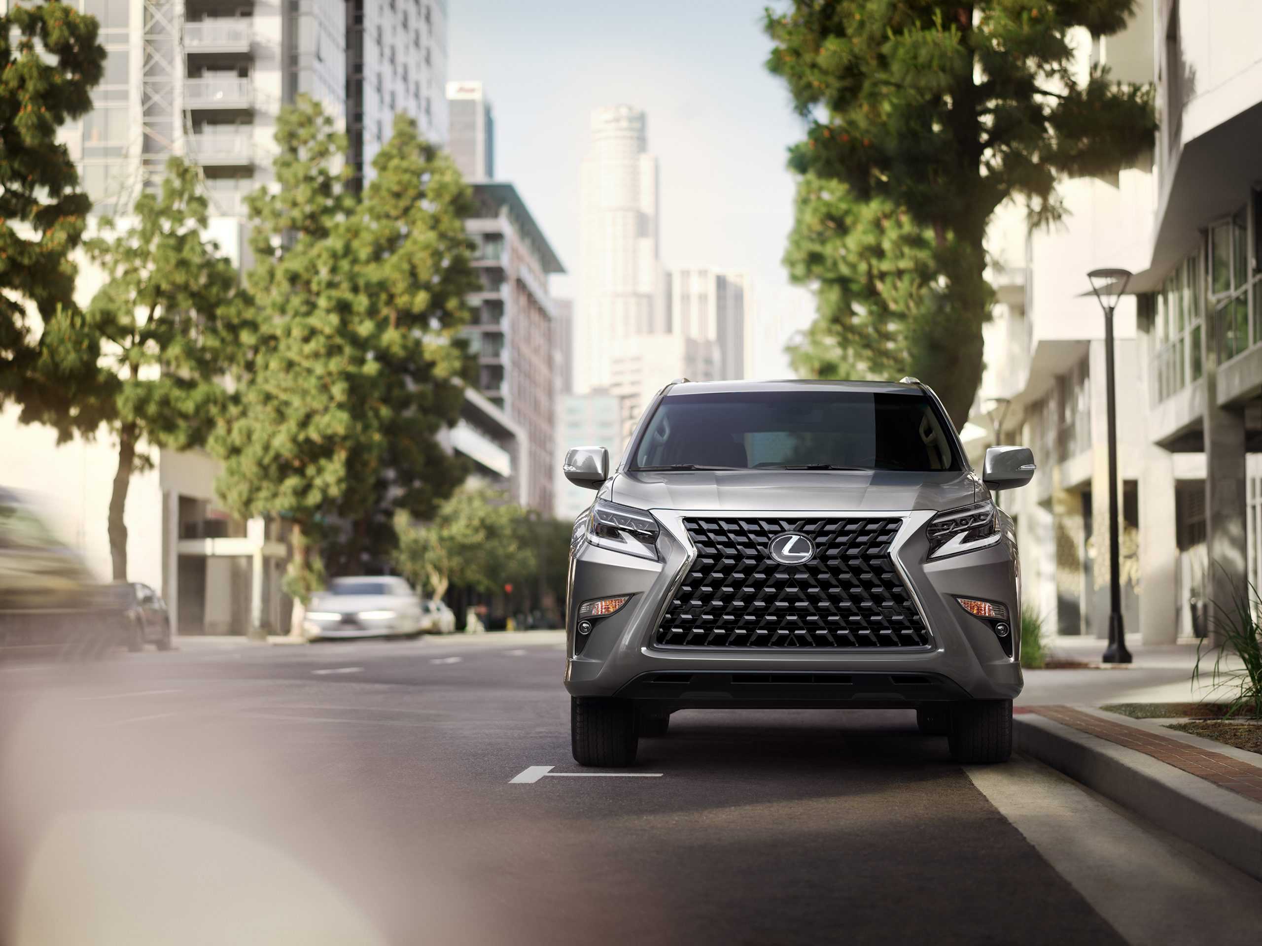 A silver Lexus GX 460 parked on a street alongside a sidewalk in a city.