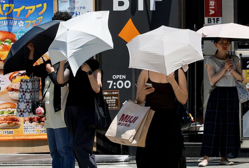 Pedestrians hold parasols to cope with the heat wave in Tokyo