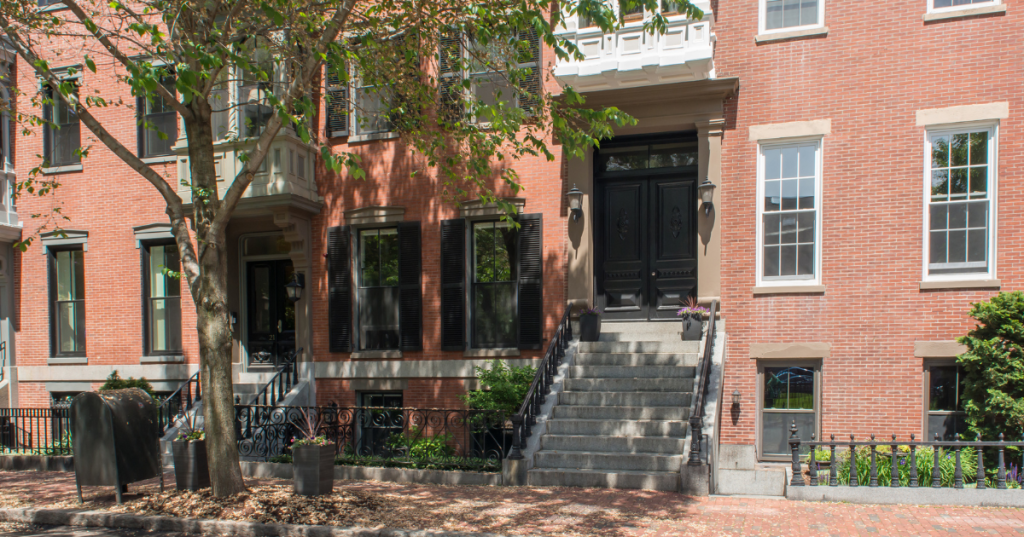 The exterior of a historic Airbnb in Boston Massachusetts, with a brick building facade and greenery surrounding.