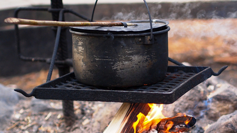 Dutch oven on a grate over a campfire.